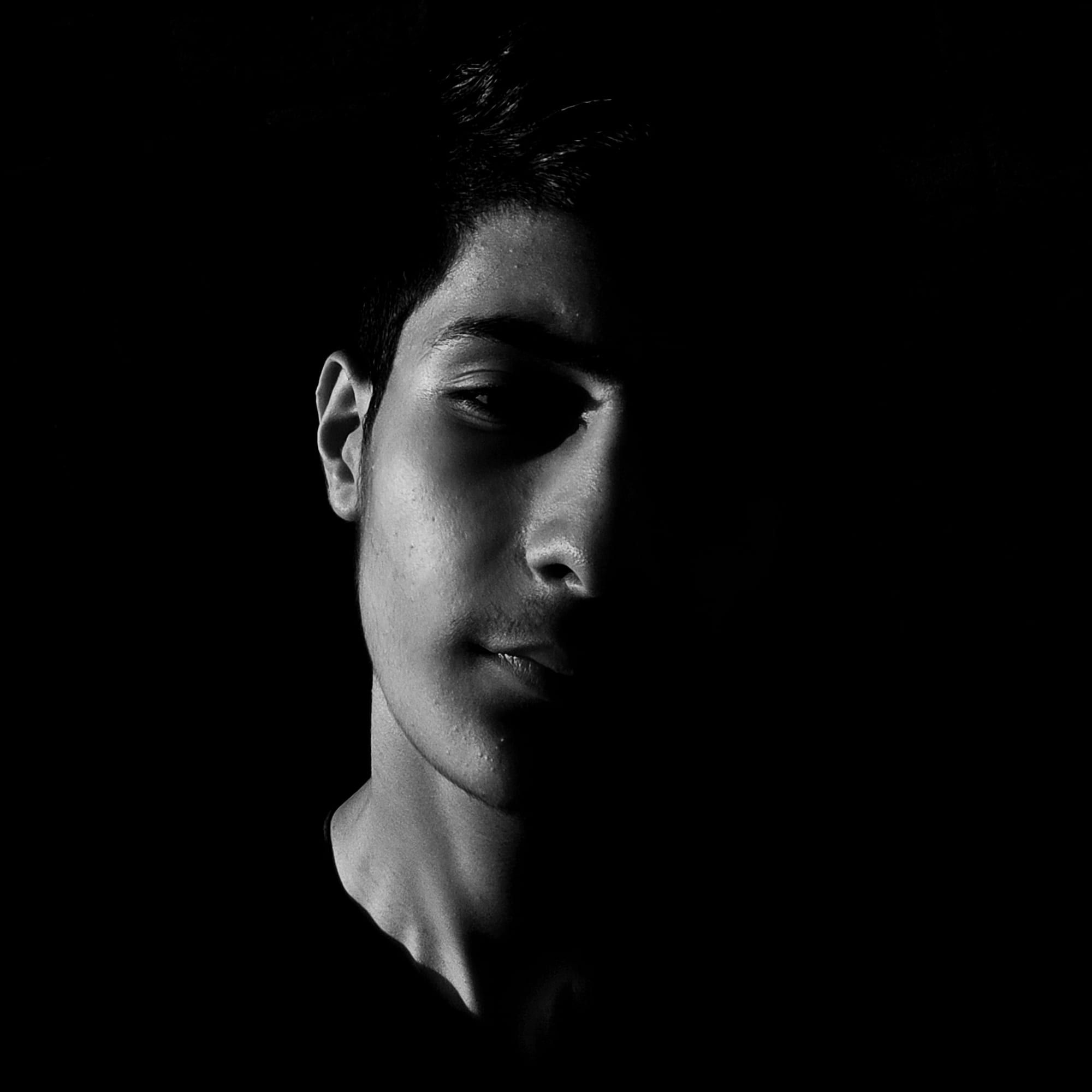 Das Gesicht eines jungen Mannes, zur Hälfte im Licht, zur Hälfte im Schatten